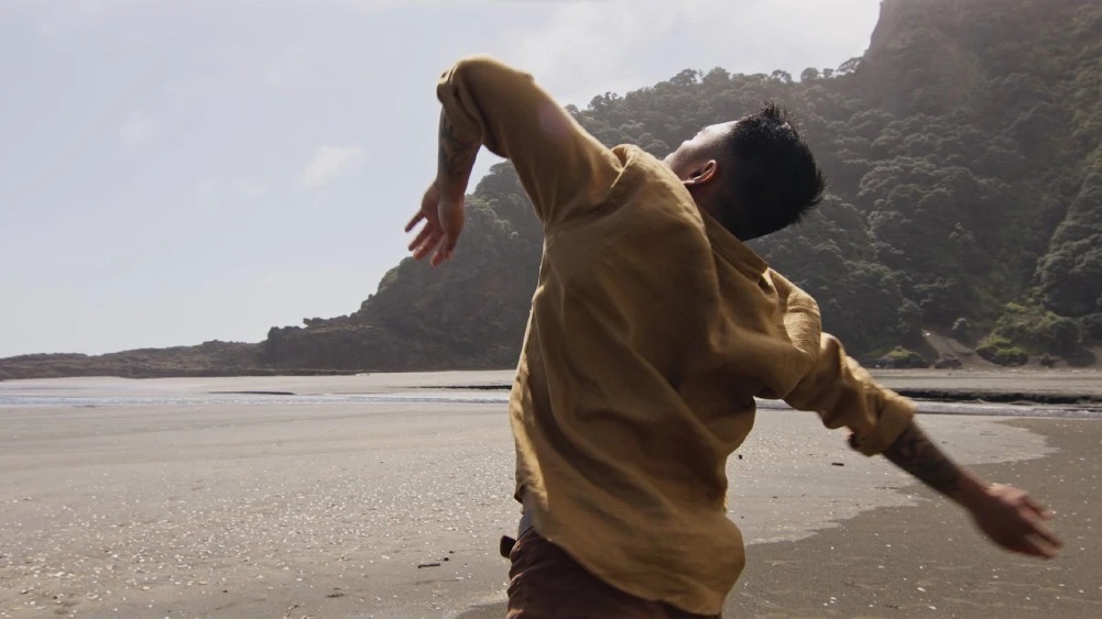 Une personne danse sur une plage, pr&egrave;s de la mer.